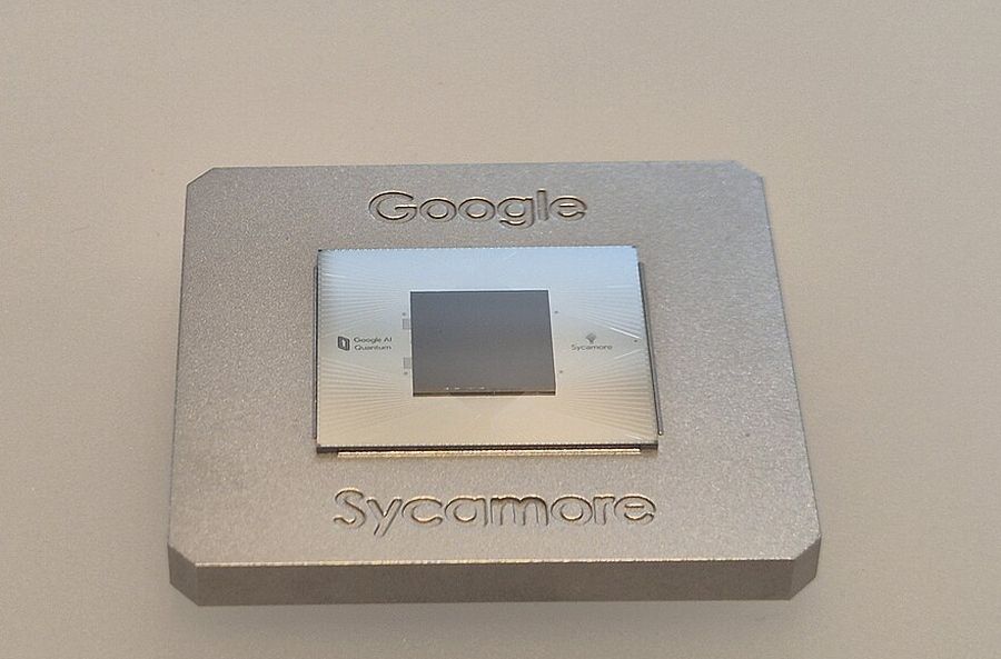 A square silicon quantum chip set in a grey metal mount engraved with the words Google and Sycamore.